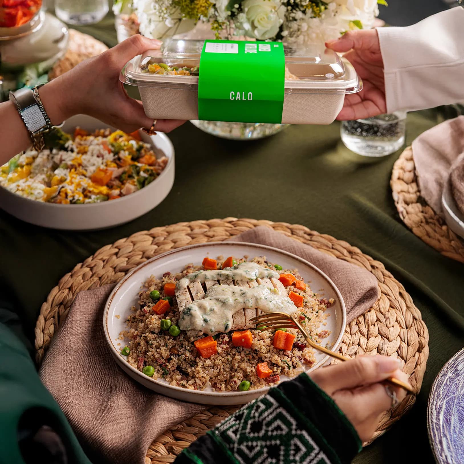 Hands passing a Calo box across a dinner table