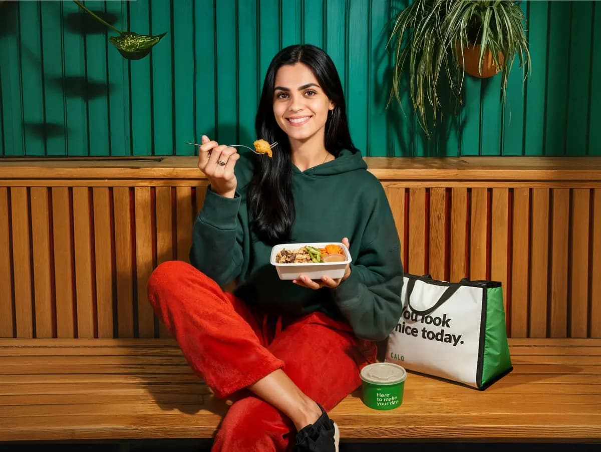 A woman enjoying a Calo meal on a bench outdoors
